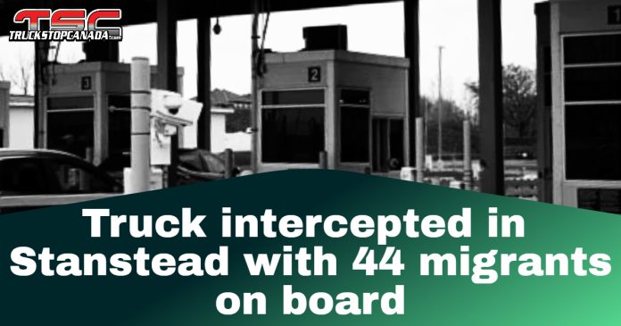 Black and white photo of a border checkpoint with surveillance cameras and inspection booths at the Stanstead border crossing, featuring the Truck Stop Canada logo and headline: “Truck intercepted in Stanstead with 44 migrants on board.”