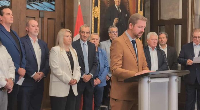 Xavier Barsalou-Duval surrounded by industry leaders including Marc Cadieux, Jean-Claude Daigneault, Éric Gignac, Yvan Domingue, and Réal Gagnon at a Bloc Québécois press conference in Ottawa on trucking reform.