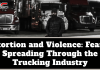 Extortion and Violence: Fear Is Spreading Through the Trucking Industry Black-and-white image of a man wearing a winter coat and beanie standing in front of several parked semi-trucks at night, with the TruckStopCanada logo at the top. Text on the image reads: “Extortion and Violence: Fear Is Spreading Through the Trucking Industry.”