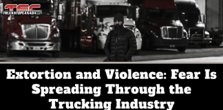 Extortion and Violence: Fear Is Spreading Through the Trucking Industry Black-and-white image of a man wearing a winter coat and beanie standing in front of several parked semi-trucks at night, with the TruckStopCanada logo at the top. Text on the image reads: “Extortion and Violence: Fear Is Spreading Through the Trucking Industry.”
